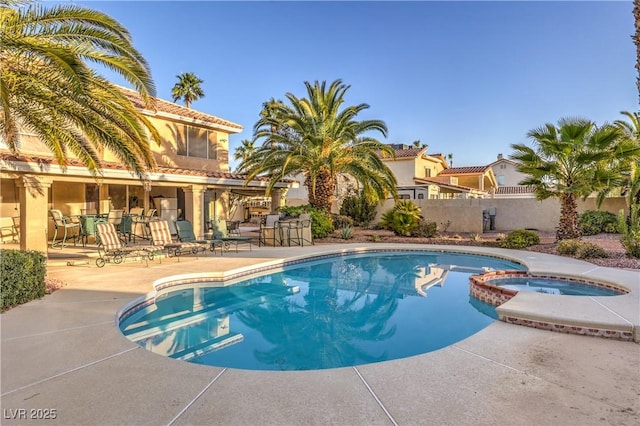 view of swimming pool with fence, a pool with connected hot tub, and a patio area