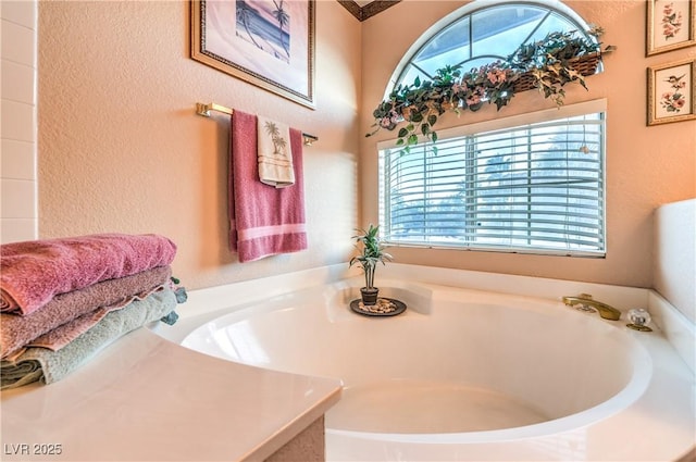 full bath with a bath, plenty of natural light, and a textured wall