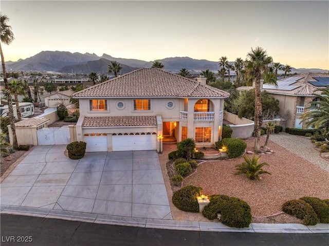 mediterranean / spanish home featuring a balcony, a gate, stucco siding, a tile roof, and a mountain view