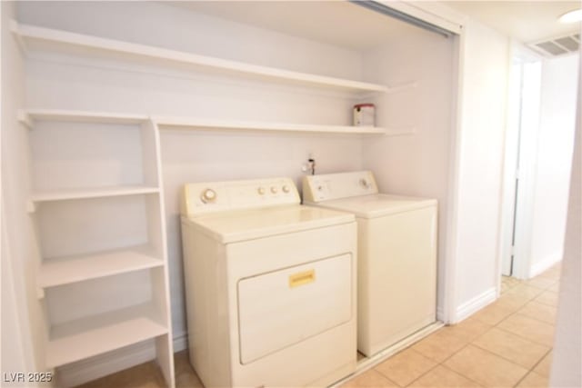 clothes washing area featuring washer and dryer, laundry area, light tile patterned flooring, and visible vents