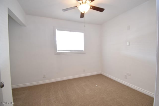 carpeted spare room with a ceiling fan and baseboards