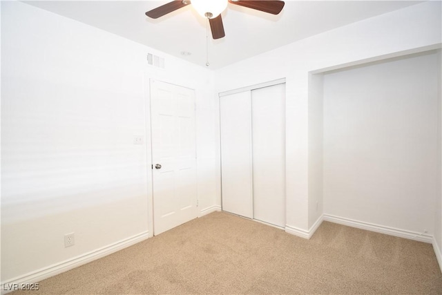 unfurnished bedroom featuring light carpet, baseboards, visible vents, ceiling fan, and a closet