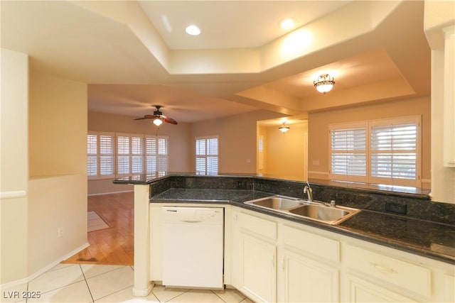 kitchen featuring a tray ceiling, light tile patterned flooring, dishwasher, and a sink