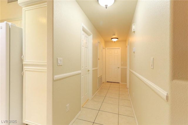 corridor featuring baseboards and light tile patterned floors