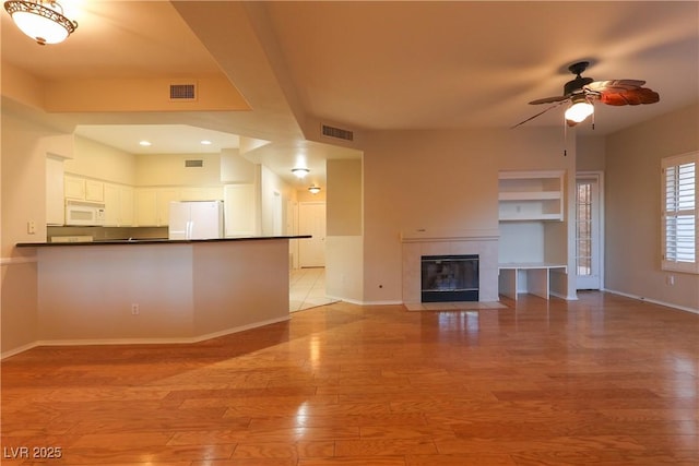 unfurnished living room featuring light wood-style flooring, a fireplace, visible vents, and baseboards