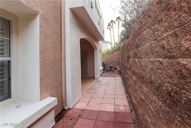 view of side of property featuring fence, a patio, and stucco siding