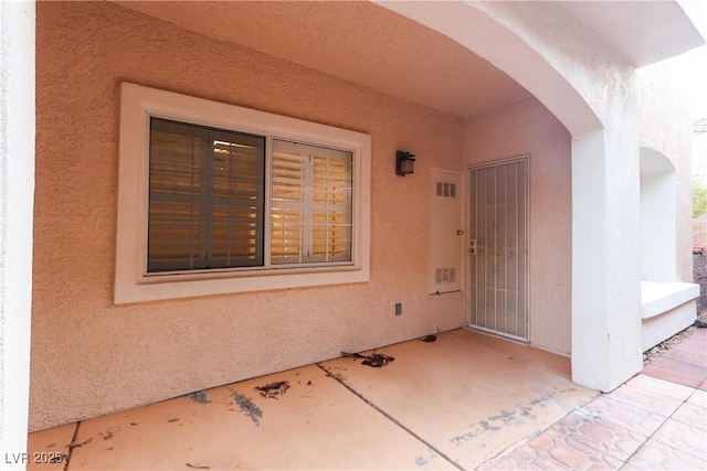 property entrance with a patio area and stucco siding