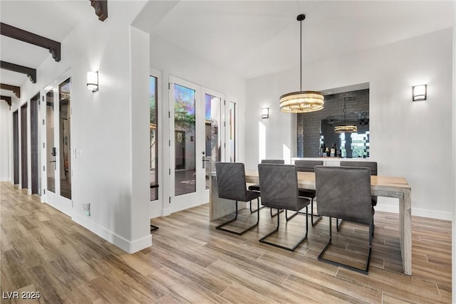 dining room with french doors, light wood-style flooring, and beam ceiling