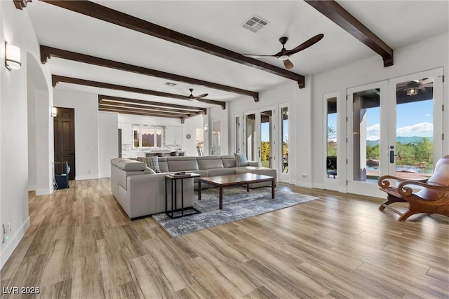 living room with a ceiling fan, light wood-type flooring, french doors, and visible vents