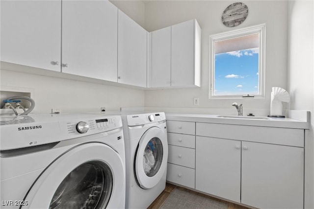 clothes washing area with washing machine and dryer, a sink, and cabinet space