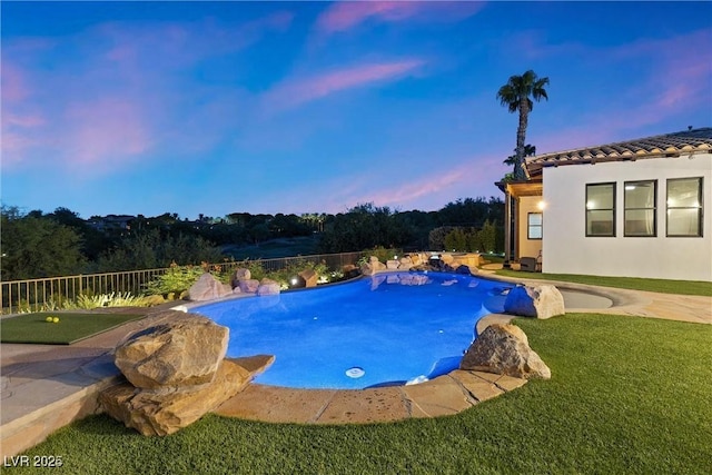 pool at dusk featuring a yard and a fenced in pool