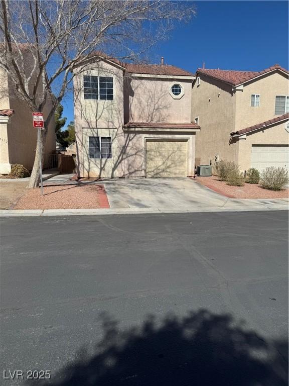 view of front facade featuring an attached garage, driveway, central AC unit, and stucco siding