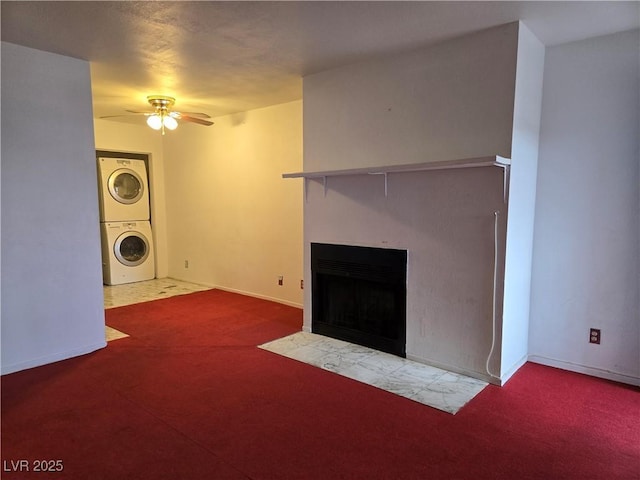 unfurnished living room with stacked washer / dryer, a fireplace with flush hearth, a ceiling fan, and baseboards