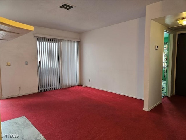 empty room featuring carpet floors, visible vents, and baseboards