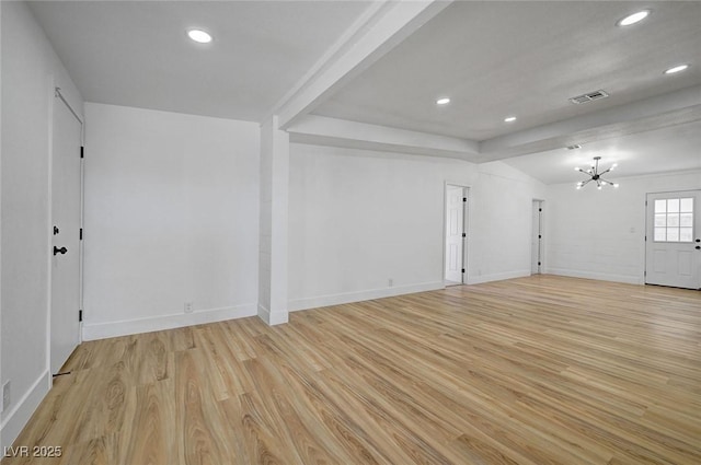 spare room with light wood-type flooring, an inviting chandelier, baseboards, and visible vents