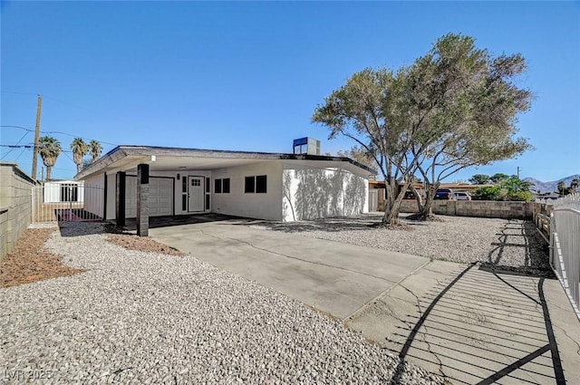 view of front of property featuring concrete driveway, an attached carport, and fence