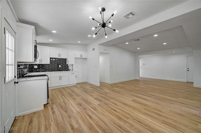 kitchen with visible vents, backsplash, light wood-style floors, white cabinetry, and range