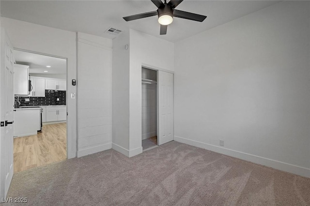 unfurnished bedroom featuring a closet, light colored carpet, visible vents, and baseboards