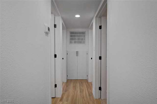 hallway featuring a textured wall and light wood finished floors