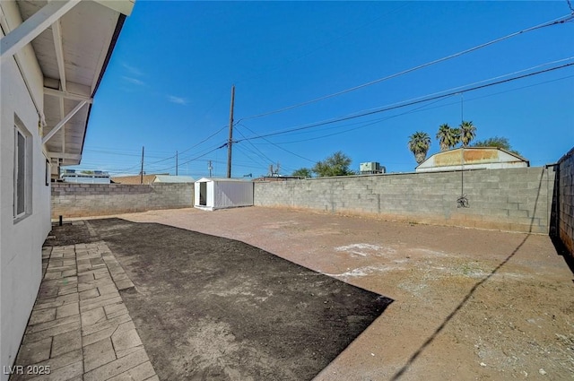 view of yard with a storage shed, a fenced backyard, a patio, and an outbuilding