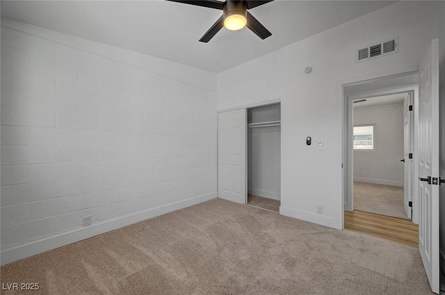 unfurnished bedroom featuring carpet, a closet, visible vents, a ceiling fan, and baseboards