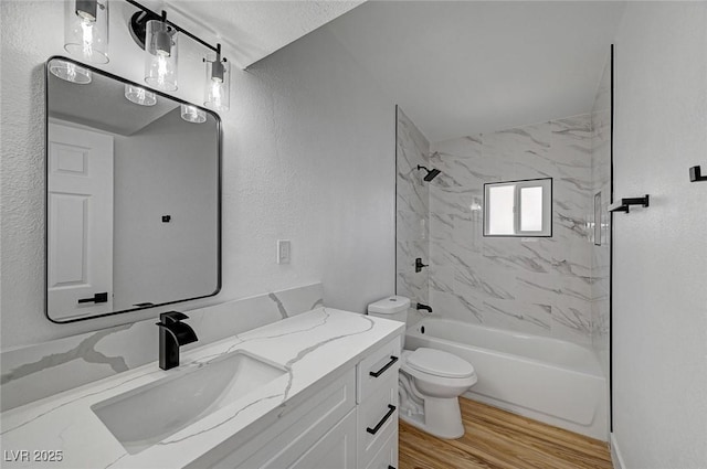 full bath with shower / bathtub combination, a textured wall, toilet, wood finished floors, and vanity