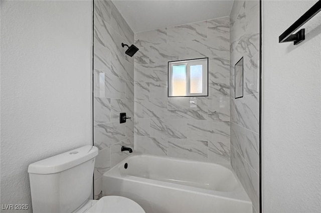 bathroom featuring a textured wall, shower / bathing tub combination, and toilet