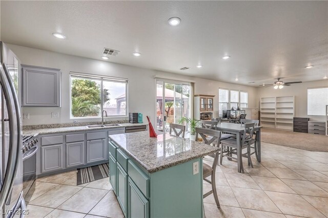 kitchen featuring light tile patterned floors, a sink, a kitchen island, visible vents, and appliances with stainless steel finishes