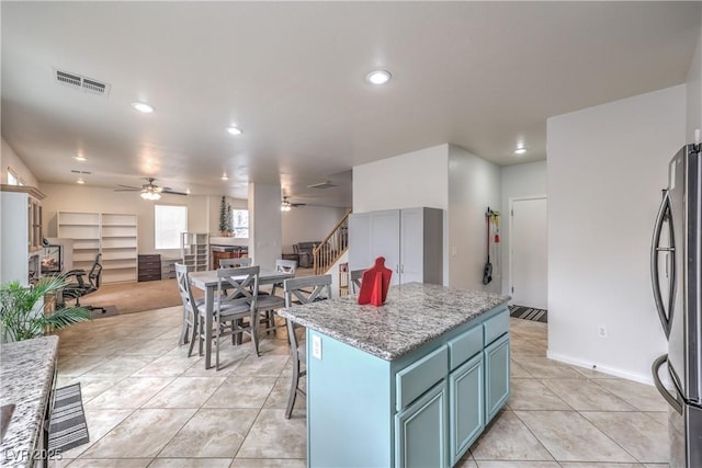 kitchen with light tile patterned floors, visible vents, ceiling fan, open floor plan, and freestanding refrigerator