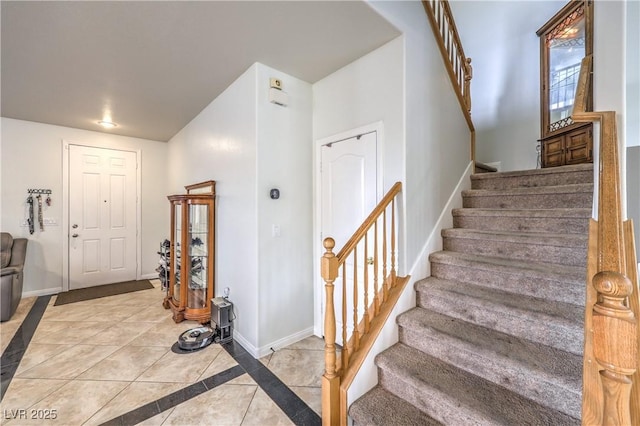 foyer entrance featuring light tile patterned floors, stairs, and baseboards