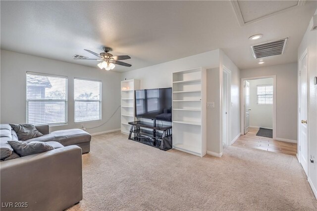 living area featuring light colored carpet, visible vents, and baseboards