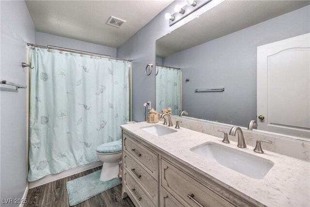 full bath with toilet, wood finished floors, a sink, and visible vents