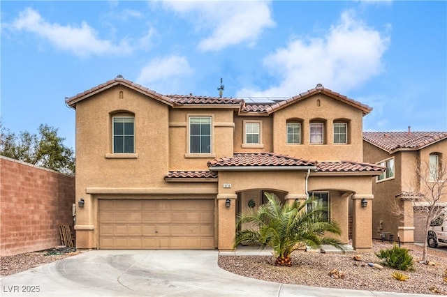 mediterranean / spanish house with a garage, roof mounted solar panels, driveway, and stucco siding