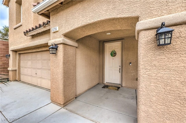 doorway to property featuring a garage and stucco siding