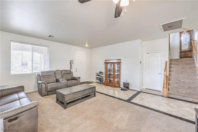 living room featuring stairway, baseboards, visible vents, and ceiling fan