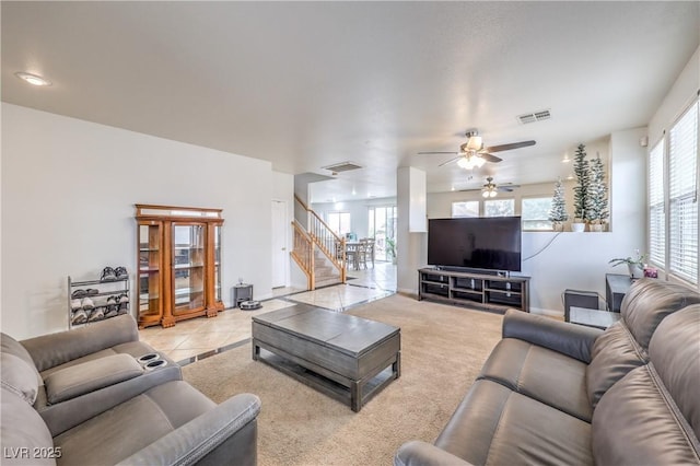 living area with light colored carpet, visible vents, stairway, and baseboards