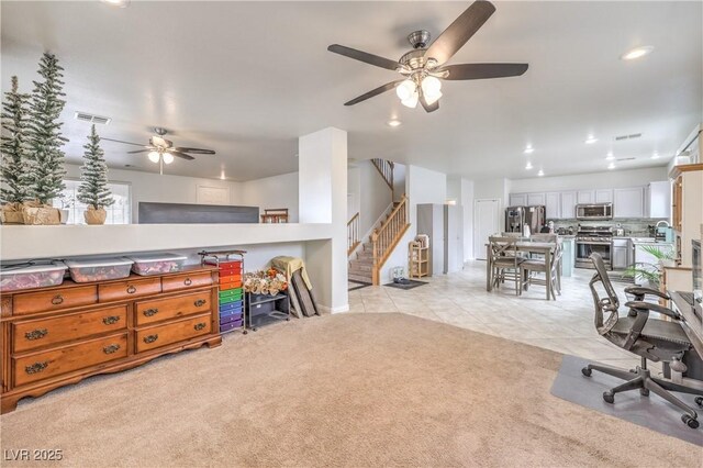 interior space with light tile patterned floors, light carpet, stainless steel appliances, a sink, and white cabinets