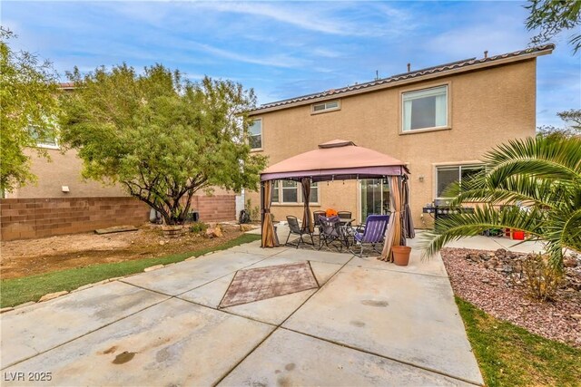 back of property with a gazebo, a patio, fence, and stucco siding