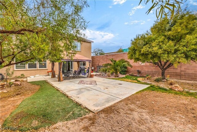 rear view of house with a fenced backyard, a patio, and stucco siding