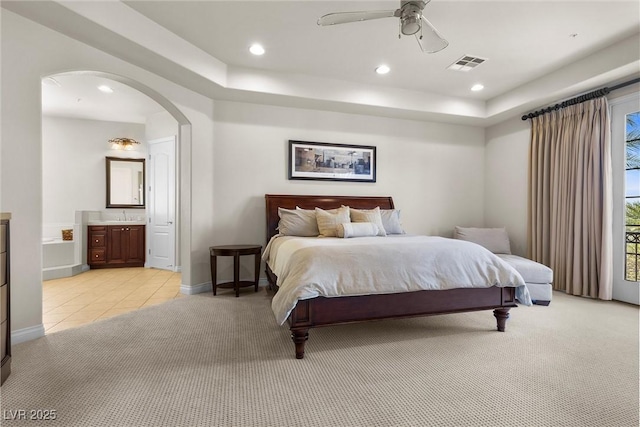 bedroom with arched walkways, recessed lighting, light colored carpet, visible vents, and ensuite bathroom