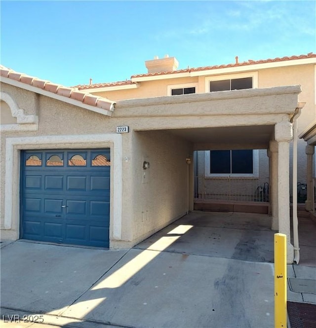 property entrance with concrete driveway, a tiled roof, an attached garage, and stucco siding