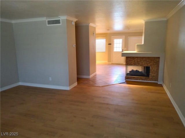 unfurnished living room featuring baseboards, ornamental molding, wood finished floors, and a multi sided fireplace