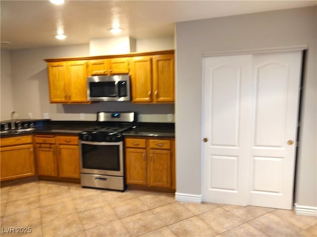 kitchen with stainless steel appliances, dark countertops, and brown cabinets
