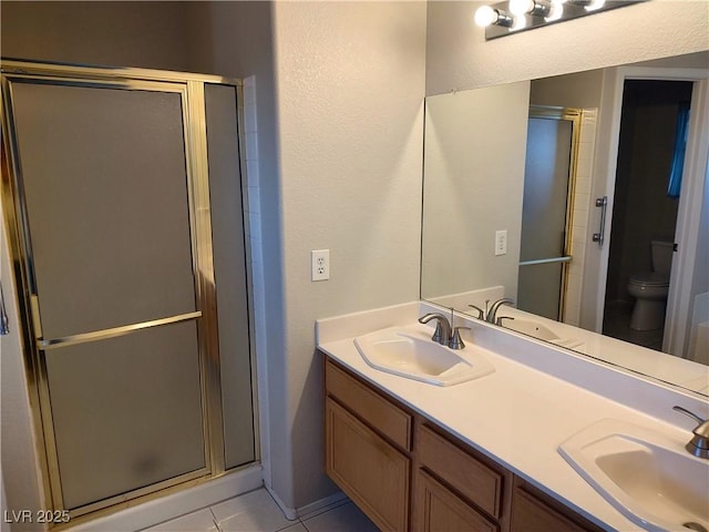 bathroom with a stall shower, a sink, and toilet