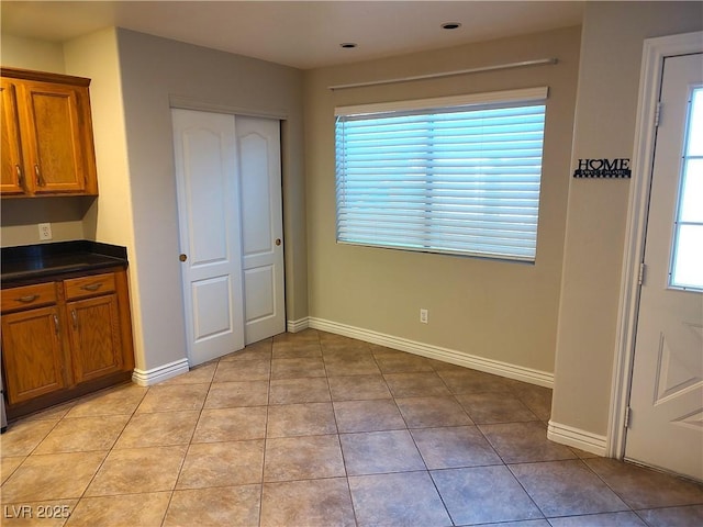 unfurnished dining area featuring light tile patterned floors and baseboards