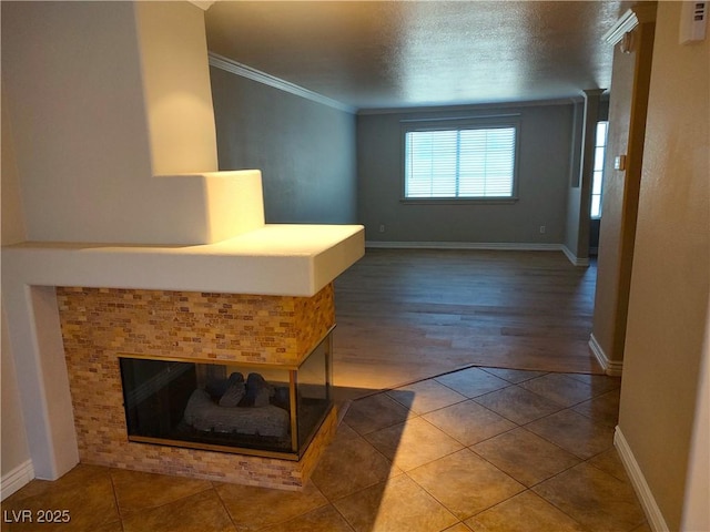 hall featuring ornamental molding, tile patterned flooring, a textured ceiling, and baseboards