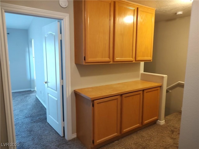corridor featuring dark colored carpet and baseboards
