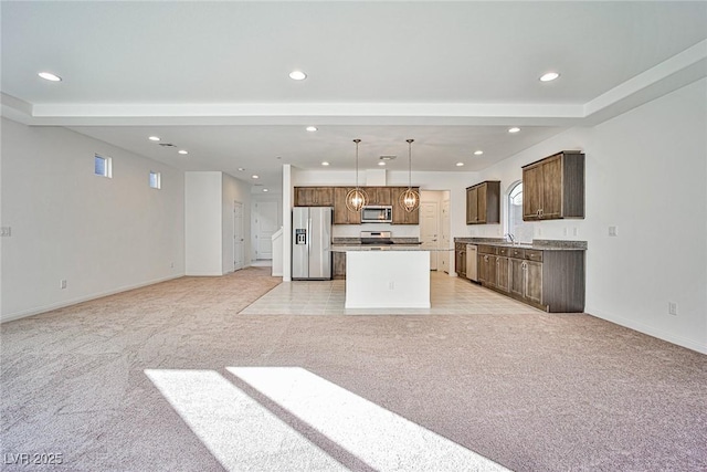 kitchen with light colored carpet, a kitchen island, appliances with stainless steel finishes, open floor plan, and recessed lighting