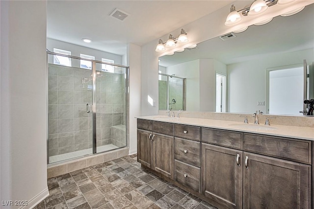 full bath featuring double vanity, a stall shower, visible vents, and a sink