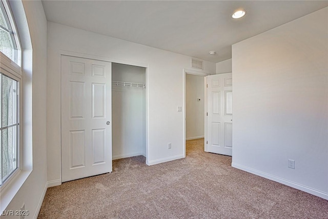 unfurnished bedroom with carpet floors, multiple windows, baseboards, and a closet